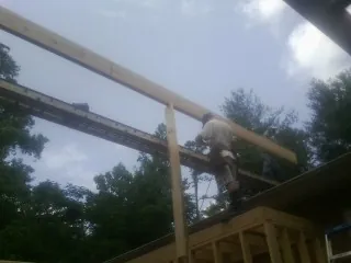 Carpenter setting a ridge beam over a new addition frame — Ice Dam Removal by Roofing Brothers in Winfred