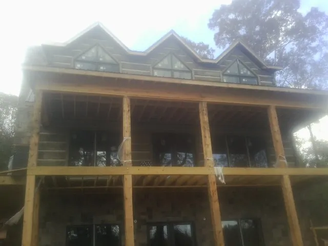 Dormers and porch framing on a large log home under construction — Roof Coating work by our crew in Winfred